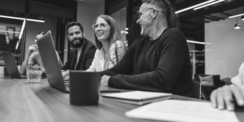 Successful group of businesspeople having a briefing in a boardroom. Happy businesspeople smiling while working together in a modern workplace. Diverse business colleagues collaborating on a project.